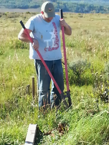 Chris Dillenbeck from F.M. Light digging fence post holes for a yellow road sign. 