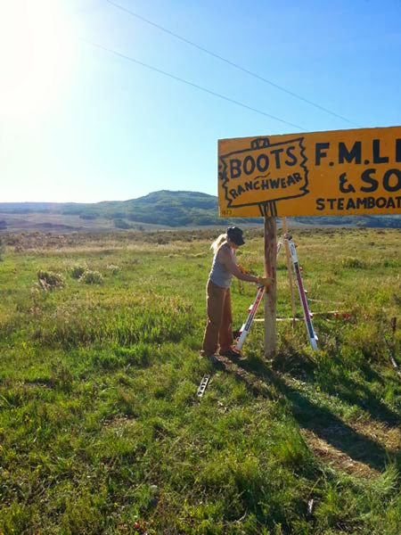 Lindsay (5th generation owner of F.M. Light and Sons) paints the posts of a famous yellow road sign.